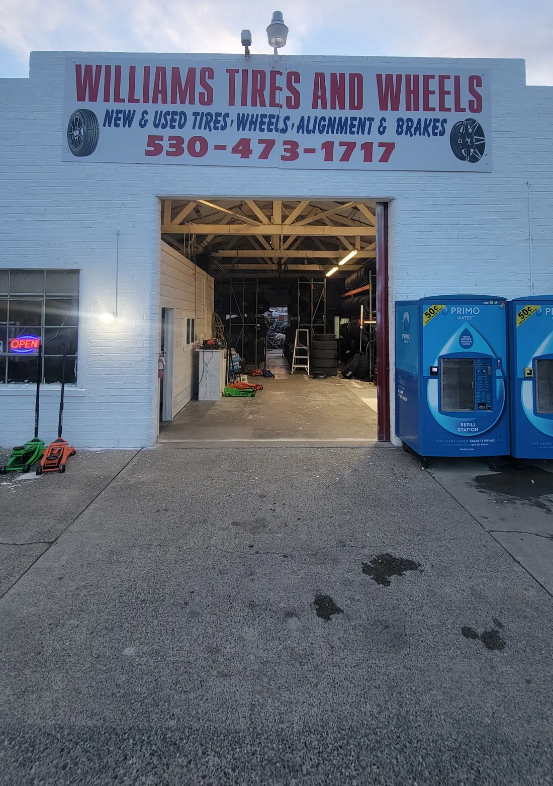 The Williams Tires And Wheels shop on Eighth Street at dusk, bay door open.